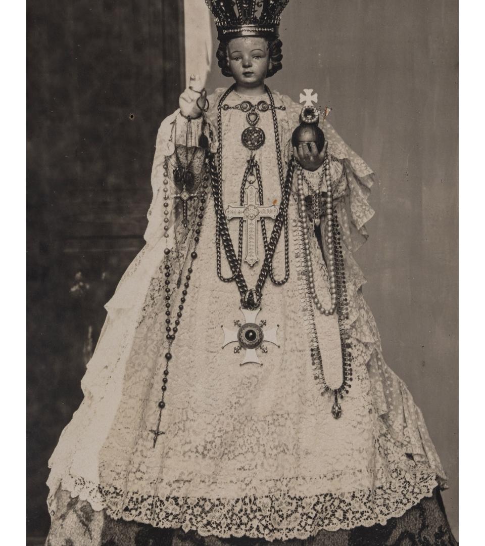 Statuette de l'Enfant Jésus en plâtre, avec sa robe en dentelle.